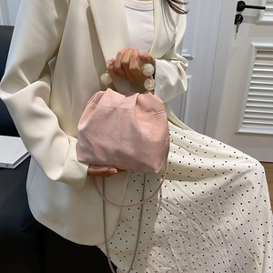 Detail of pink dumpling bag featuring marble texture bead handle and delicate metal chain