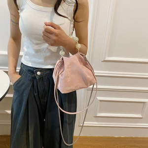 Detail of pink dumpling bag with large pearl handle and metal chain on a model