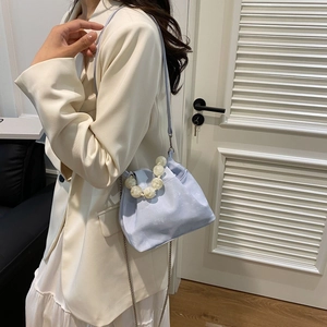 Detail of light blue cloud bag featuring frosted large pearl handle and pleated satin texture