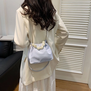 Detail of light blue satin cloud bag with large pearl handle and thin metal chain strap