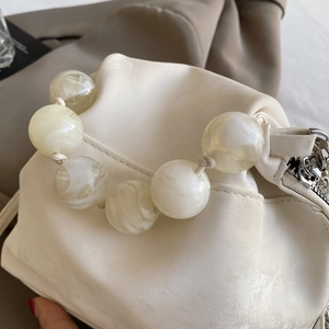 Detail of matte cream cloud bag featuring large marble texture resin bead handle