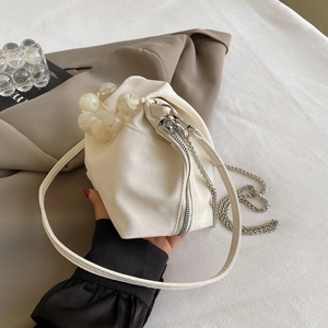 Detail of white pleated cloud bag with large marble-beaded handle and chain strap