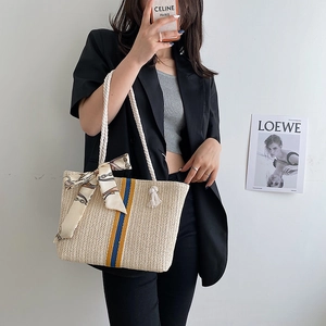Woven straw tote bag with blue and yellow stripes and decorative silk scarf handle