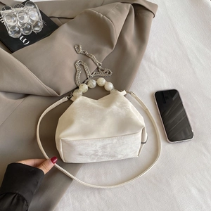 Detail of cream cloud bag with marble bead handle and metallic chain strap on a blazer