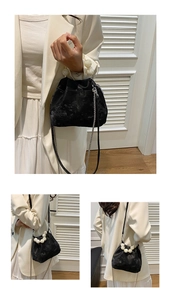 Detail of black velvet bucket bag with large pearl handle and silver chain strap