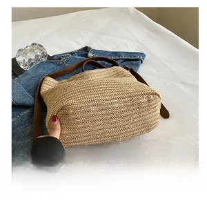 Detail view of the durable woven straw bag base with premium brown leather strap accents