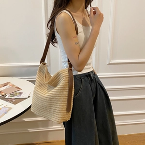 Straw shoulder bag with brown leather strap worn by a model for a summer resort look