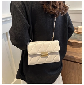 Détail du sac bandoulière crème avec surpiqûres en V et chaîne dorée élégante