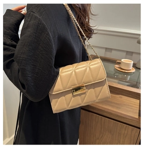 Détail d'un sac bandoulière matelassé beige avec fermoir doré porté par mannequin