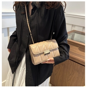 Détail du petit sac beige matelassé avec fermoir doré et bandoulière en chaîne
