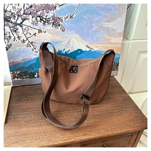 Macro detail of brown nylon crescent bag with adjustable strap and orange side label