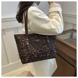 Detail of leopard print tote bag with brown leather shoulder straps and metal rivets
