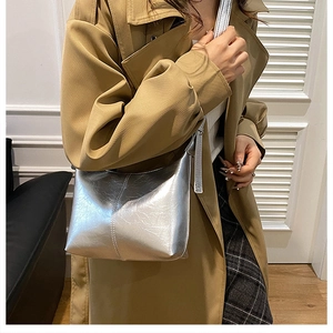 Close-up of a silver crescent bag with cracked texture worn with a trench coat