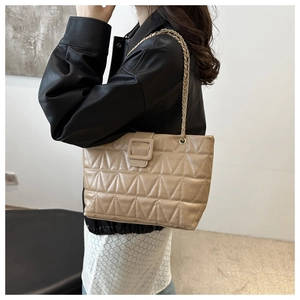 Dettaglio borsa a spalla trapuntata beige con cuciture a triangolo e catena dorata