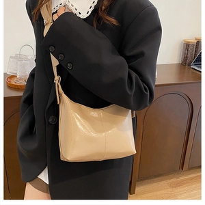 French crescent shoulder bag in light beige PU leather worn by a model in a home setting