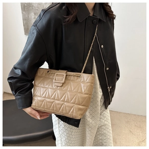 Dettaglio borsa a tracolla trapuntata beige con catena e fibbia sulla modella