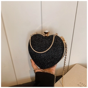 Dettaglio di una pochette da sera nera a forma di cuore con glitter e manico dorato