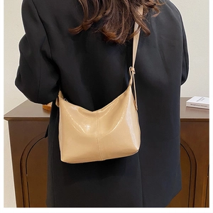 Close-up of beige glossy PU leather handbag with fine stitching and shoulder strap