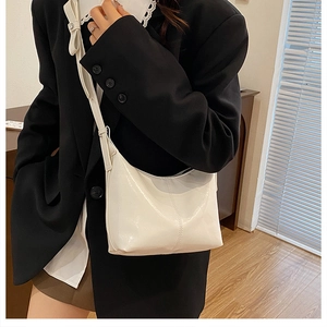 Detail of white glossy crossbody bag with contrast stitching and adjustable strap
