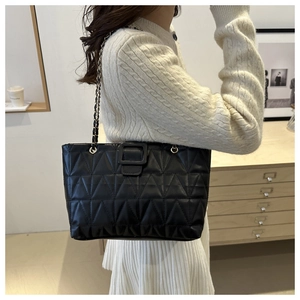 Dettaglio borsa tote trapuntata nera con tracolla a catena e cuciture eleganti