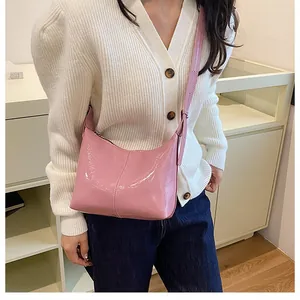 Pink patent leather crescent shoulder bag styled with white cardigan and blue jeans