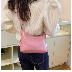 Detail view of pink crescent shoulder bag in glossy patent leather on model
