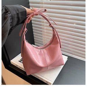 Detail of pink patent leather tote bag with glossy finish and stylish bow decoration