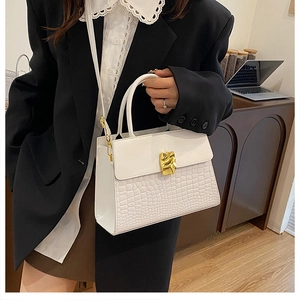 Detail of white crocodile pattern bag with vintage gold hardware and elegant metal clasp