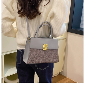 Detail of greyish purple crossbody bag with unique golden metal clasp and croc texture