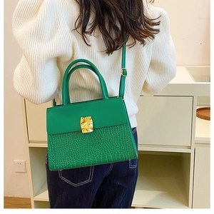 Detail showing green leather crossbody bag with crocodile texture and gold metal buckle