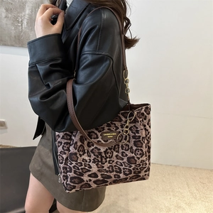 Large leopard print tote bag with gold chain and thin straps shown from a side view
