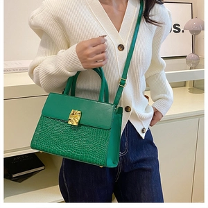 Detail of green crocodile texture flap bag with stylish gold metal buckle and strap