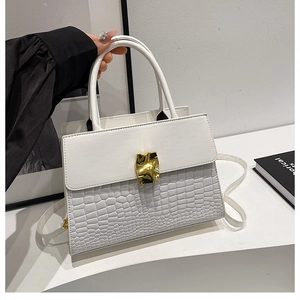 Detail view of white flap bag featuring crocodile embossed texture and gold metal buckle