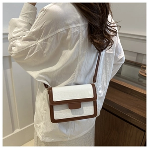 Detail of a white and brown crossbody square bag with crocodile texture on a model