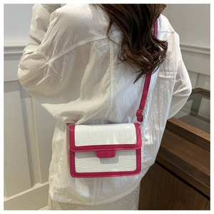 Detail of white crocodile texture crossbody bag with vibrant pink trim and adjustable strap