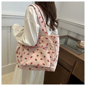 Detail of pink corduroy tote bag with red strawberry print and functional front zip pocket