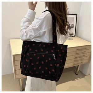 Woman wearing black strawberry print corduroy shoulder bag in a minimalist home setting