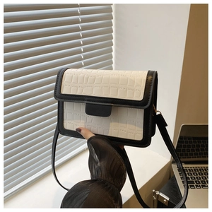 Detail of black and white crocodile pattern small square bag with sleek shoulder strap