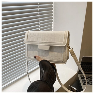 Detail of cream white faux crocodile leather texture on stylish crossbody square bag