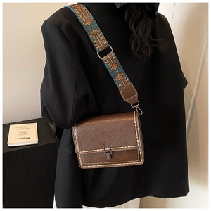 Detail of vintage brown leather crossbody bag with ethnic patterned wide strap and studs