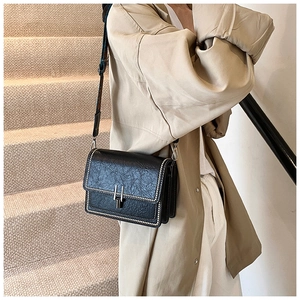 Close-up of black retro leather crossbody bag with silver studs and geometric strap