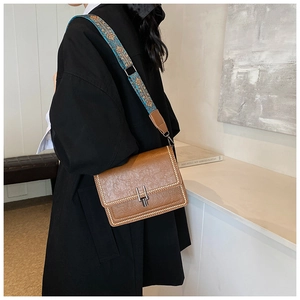 Brown vintage leather shoulder bag with metallic studs and blue floral jacquard strap