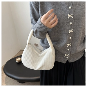 Detailed texture of white corduroy pillow bag with smooth zipper and minimalist handle