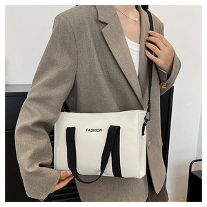Détail du sac cabas en toile avec poignées noires contrastées et bandoulière réglable
