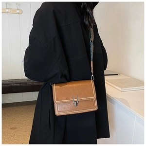 Detail of vintage brown crossbody bag with metal latch and embroidered wide strap