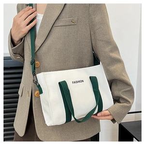 Détail d'un sac cabas en toile blanche avec poignées vert foncé et bandoulière réglable