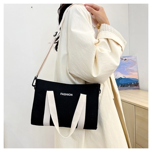 Détail du cabas en toile noire avec poignées blanches et logo FASHION imprimé à l'avant