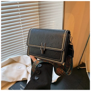 Close-up of black pleated leather crossbody bag with gold rivets and bohemian strap