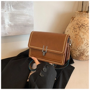 Detail of vintage brown leather crossbody bag with gold studs and ethnic woven strap