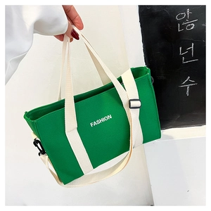 Vue détaillée du sac cabas en toile verte avec lettrage FASHION et bandoulière blanche